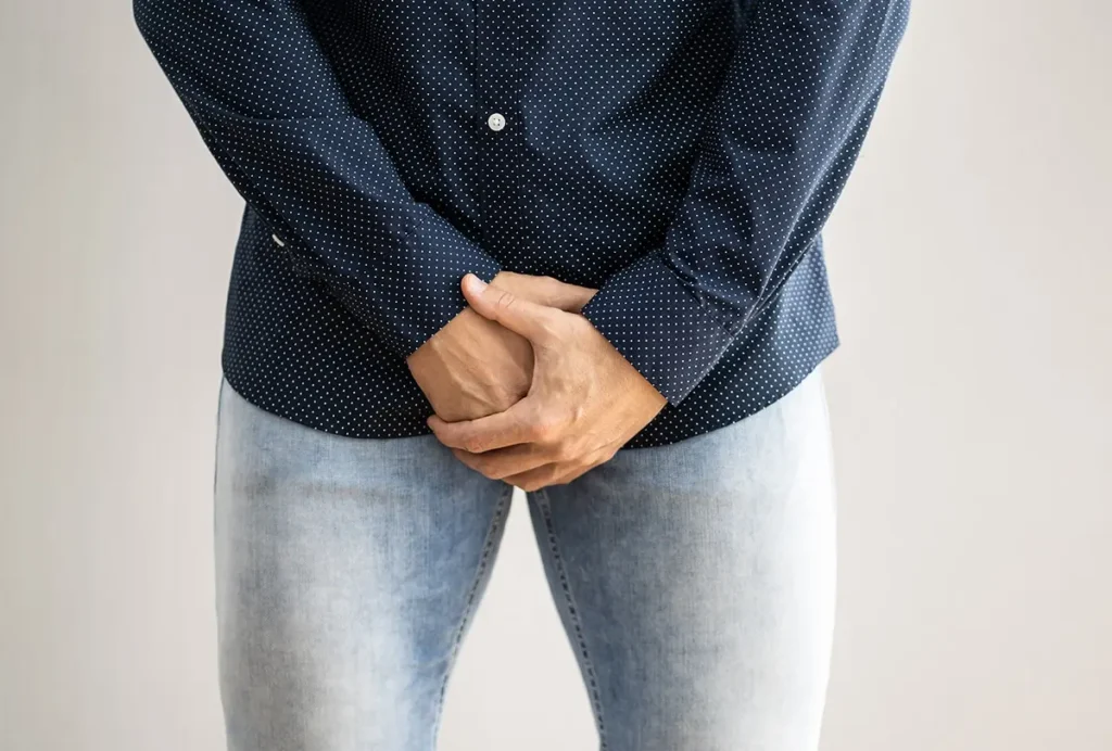 Man holding his groin area, possibly experiencing pain or discomfort.